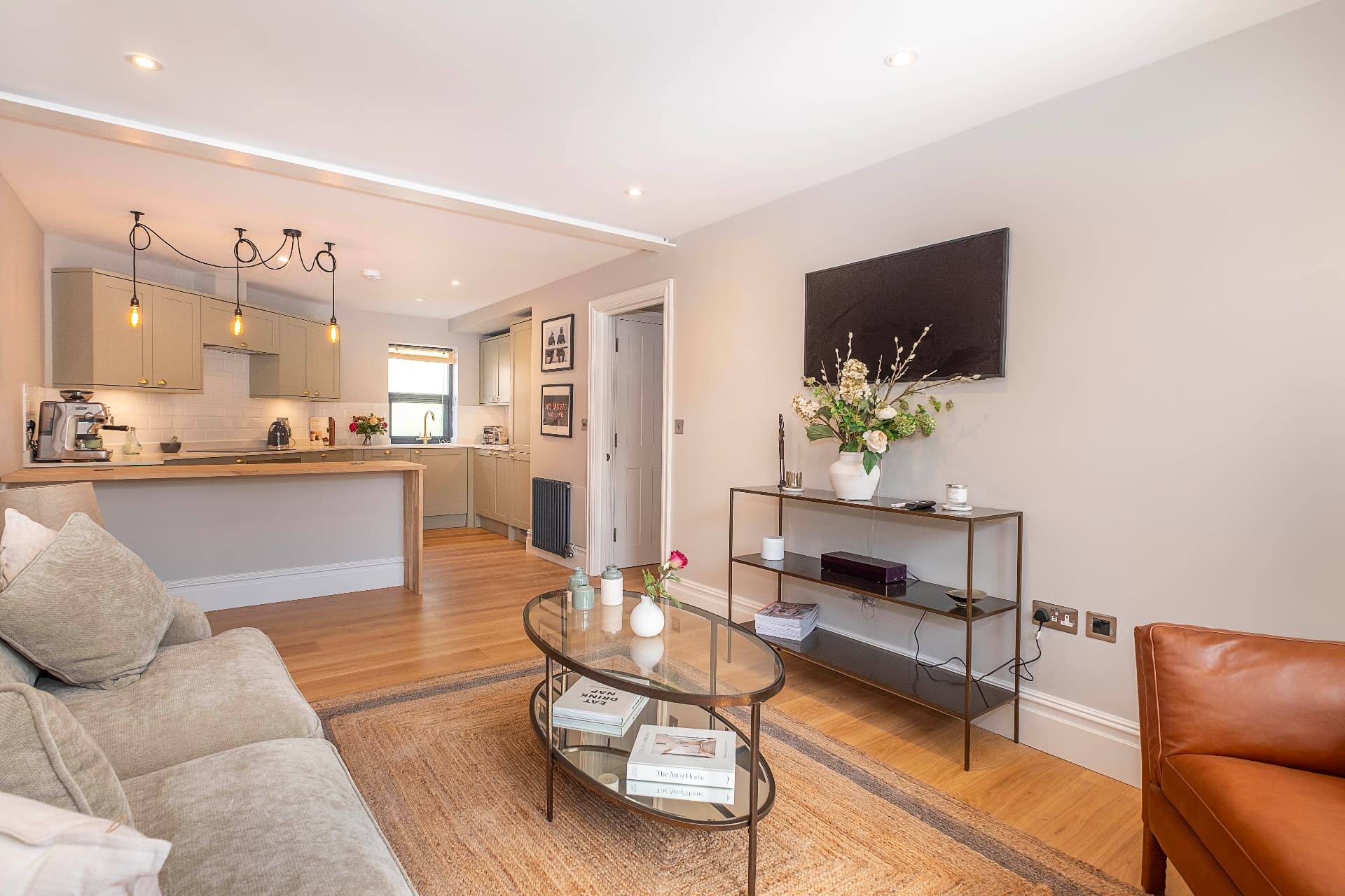 Living room with a sofa, coffee table and rug facing the open kitchen