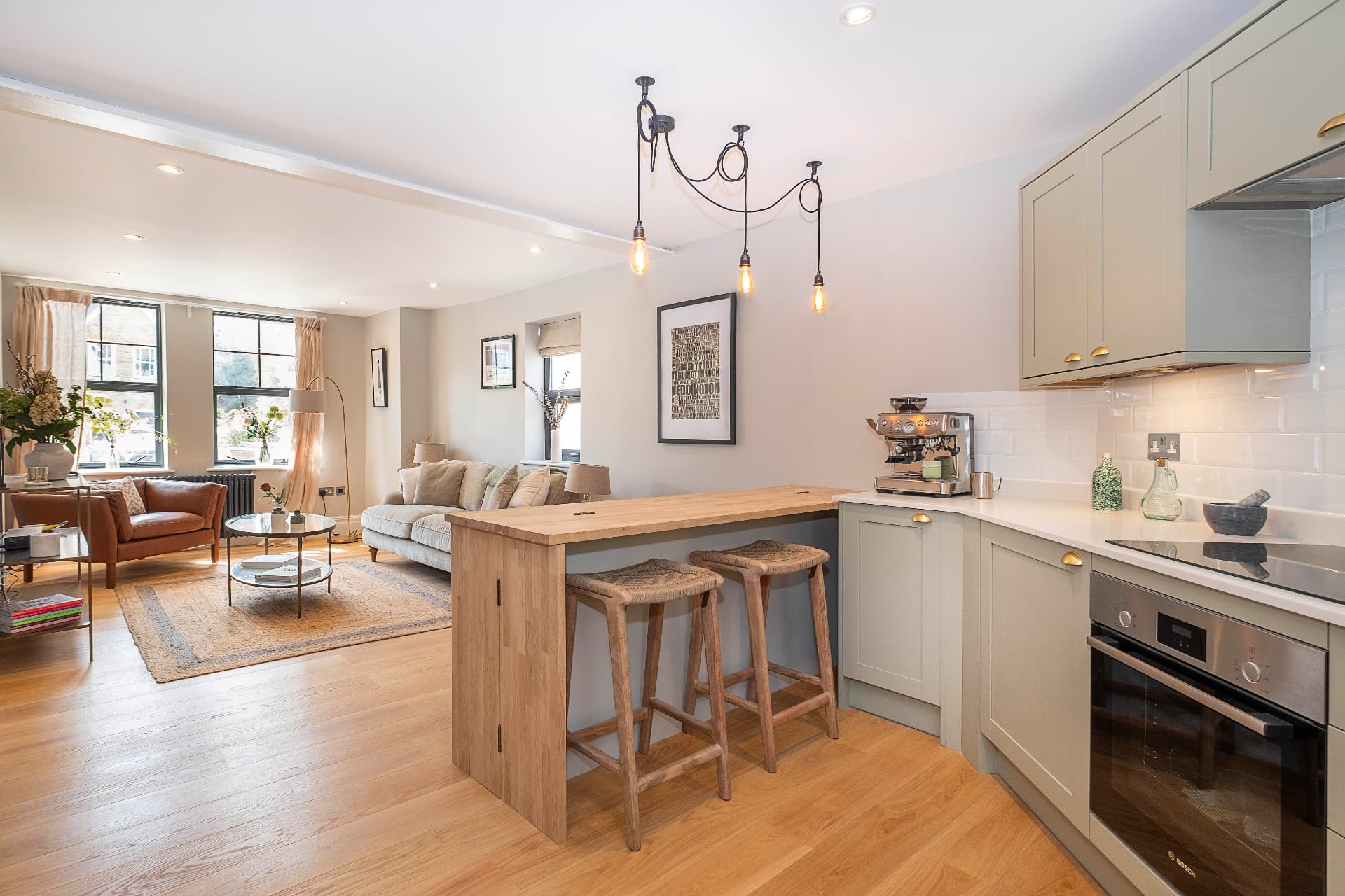 Open plan kitchen and living room with a wooden breakfast bar and pendant lights